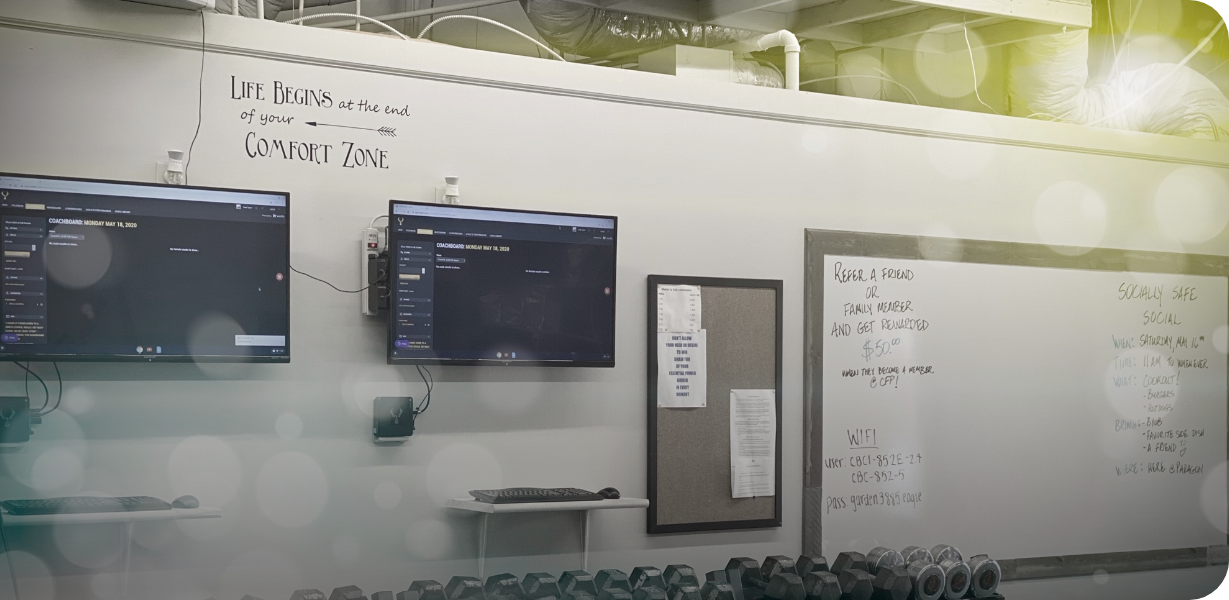 CFP gym wall showing boards and TV screens with notes of schedules, CrossFit workout plans and motivating words